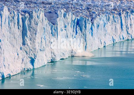 Ice breaking off Perito Moreno Glacier and falling into turquoise water in Patagonia Argentina, dramatic calving event and climate change concept Stock Photo