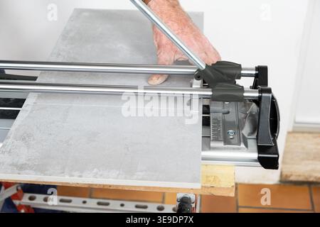 the mason cuts a ceramic tile with a tile cutter Stock Photo