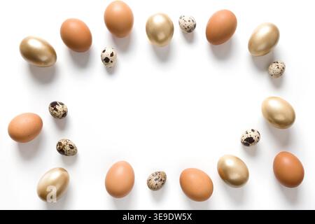 Easter frame of golden, quail, chicken eggs on white background. View from above. Space for text. Stock Photo