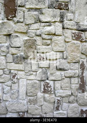 Stone wall surface with light gray stones, scattered brown painted stones, porous mortar, and rectangular uneven stones Stock Photo