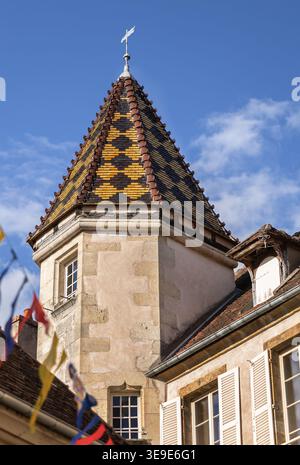 A close-up of a pyramidal roof covered with traditional Burgundian glazed terracotta tiles. The multicolored tiles are arranged in a vibrant diamond p Stock Photo