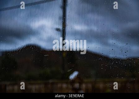 Abstract moody view of the Scottish Highlands countryside seen through a rain-splashed window during a storm in Perthshire Stock Photo
