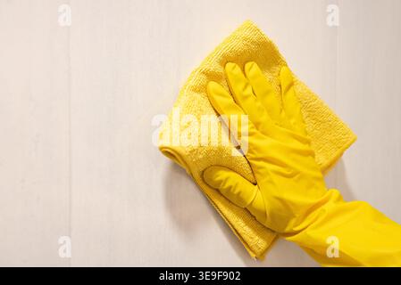Close-up of a hand gripping a folded yellow microfiber cloth, ideal for cleaning, household chores, and hygiene-themed advertising or lifestyle conten Stock Photo