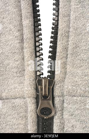 open black plastic zipper on gray sweatshirt material isolated white background, close-up macro view in vertical orientation Stock Photo