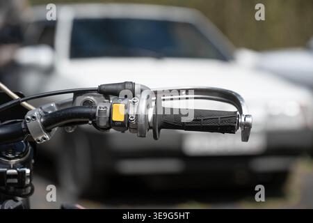 Close-up of a motorcycle handlebar with controls and yellow switch. Stock Photo