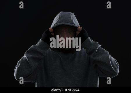 Anonymous man with pixelated face in hoodie on black background Stock Photo