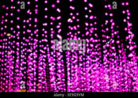 Abstract pink bokeh lights cascading on a dark background Stock Photo