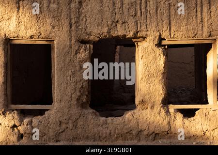 Old mud wall with small windows and weathered texture reflecting traditional Omani architecture and historic rural style, Oman Stock Photo