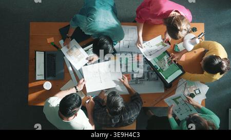 Top aerial view of civil engineer holding and asking project manager about plan. Group of architect brainstorming and explaining blueprint while Stock Photo