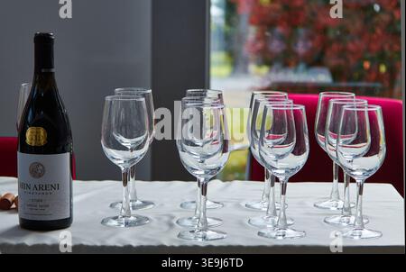 Burgas, Bulgaria - April 17, 2026: Armenian wine bottle labeled Hin Areni placed next to a series of empty wine glasses on a table in an exhibition sp Stock Photo