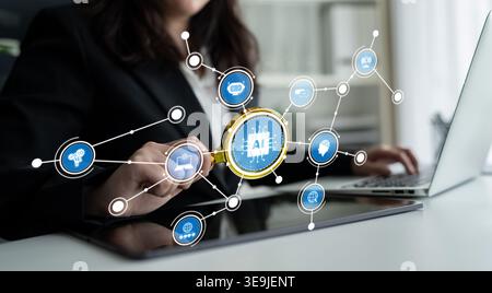 A businesswoman examines artificial intelligence concepts using a magnifying glass while working on a laptop. This image illustrates the significance Stock Photo