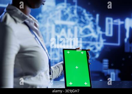Experienced developer uses mockup tablet to update neural networks, writing intricate binary code scripts on tablet. Worker uses isolated screen device programming to upgrade AI simulation model Stock Photo