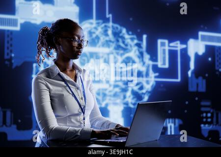 BIPOC woman developing artificial intelligence neural networks architecture inspired by human brain. Tech support setting up AI machine learning algorithms in high tech startup Stock Photo