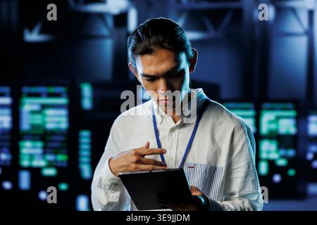 Tech support worker between server hub clusters providing processing resources for businesses worldwide. Overseeing supervisor fixes data center mainframes used for managing massive databases Stock Photo