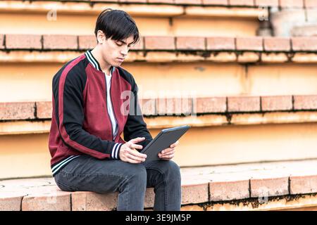 Young man studying digital tablet on steps Stock Photo
