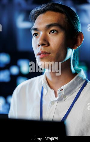 Portrait of technician between server hub clusters providing processing resources for businesses worldwide. Experienced professional fixes data center mainframes tasked with managing massive databases Stock Photo