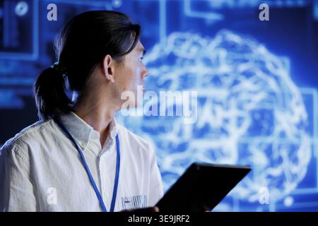 Computer scientist using tablet to maintenance artificial intelligence neural networks simulating human thought processes in computerized model. Tech support doing checkup on AI systems Stock Photo