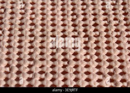 Angled macro shot showing the depth and texture of a beige non-slip mesh underlay mat Stock Photo