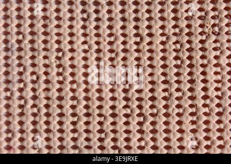 Macro full frame texture of a non-slip underlay mat with a beige mesh grid pattern Stock Photo