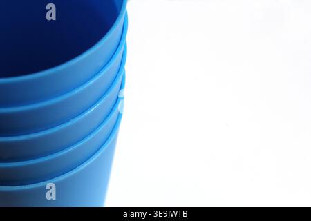 Close-up of a stack of vibrant blue plastic cups against a clean white background, featuring a minimalist, modern aesthetic Stock Photo