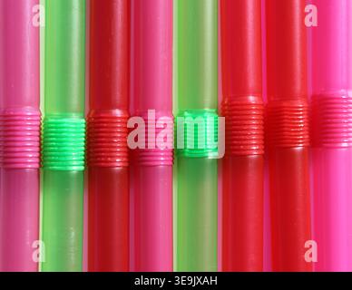 Top-down macro shot of vertical red, pink, and green flexible plastic drinking straws arranged in a colourful row Stock Photo