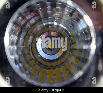 Extreme macro close-up of a modern LED spotlight bulb interior showing clear reflector lens and central light-emitting diode Stock Photo