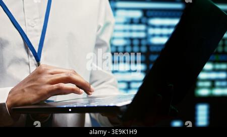 Engineer in data center walking through server racks used for computationally intensive tasks such as quantum mechanics or weather forecasting. Expert running routine equipment diagnosis, close up Stock Photo
