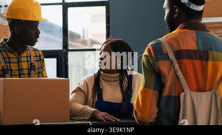 Team of employees doing quality control in storage room, planning shipment distribution with cardboard packages. Young people working on stock inventory for retail store delivery. Stock Photo