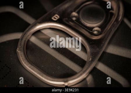 Macro closeup of metal pull tab on food can lid showing ring mechanism and textured surface of sealed container Stock Photo