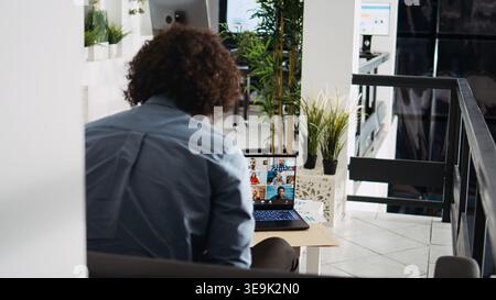 Businessman meeting on videocall with colleagues, presenting new company development vision in agency office. Employee talking on online teleconference remote call, briefing chat. Stock Photo