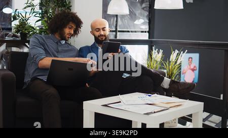 Two managers checking reports and official documents in coworking space office. Smiling entrepreneurs team working together on development plan for small business project, collaboration. Stock Photo