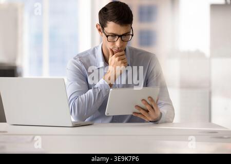 Focused man analyzing data on digital tablet Stock Photo