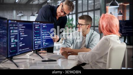 Software Engineer Coding On Computer While Collaborating With Diverse Team. Stock Photo
