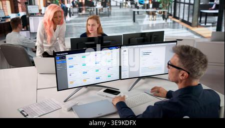 Project Manager Reviewing Workflow Documents On Computer For Team Collaboration. Stock Photo