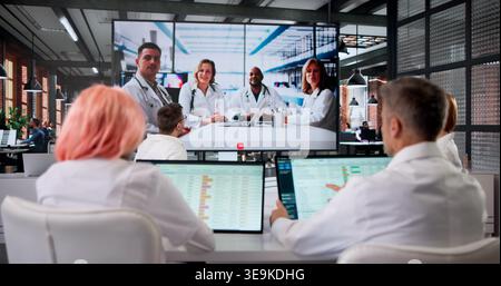 Doctor Leads Medical Conference Webinar While Nurses Watch Attentively On Screen. Stock Photo