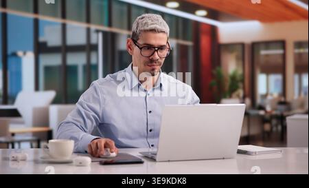 Hispanic Entrepreneur Concentrating On Laptop In Home Office Setting Stock Photo