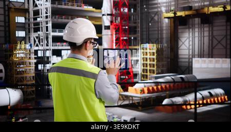 Hispanic Engineer Designs Sophisticated Automation Controls On Tablet In Aerospace Facility Stock Photo