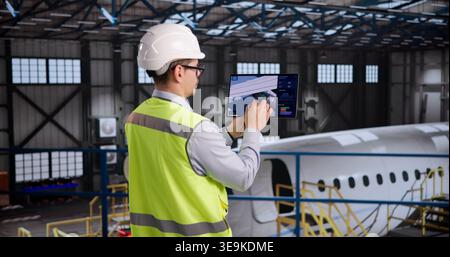 Aerospace Technician Inspecting Aircraft Components With A Tablet In Hangar Stock Photo