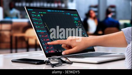 Young Trader Analyzing Stock Market Trends While Working On Laptop In Office. Stock Photo