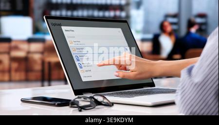 Young Woman Uploads Important Work Files To Cloud While Enjoying Coffee. Stock Photo