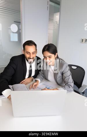 Smiling multiethnic colleagues collaborating on project using laptop Stock Photo