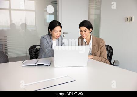 Colleagues collaborating on project, reviewing digital data using laptop Stock Photo
