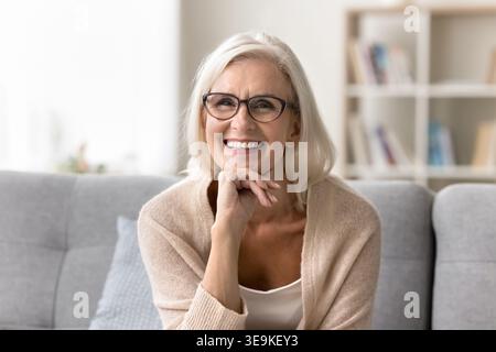 Portrait of mature woman posing for camera seated on sofa Stock Photo