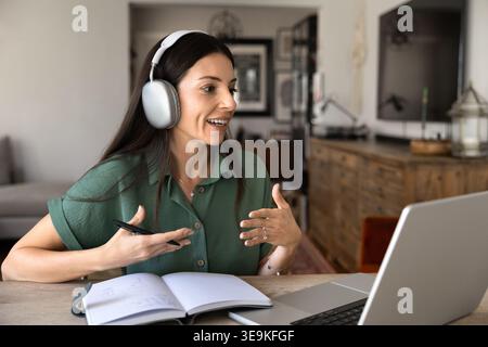 Adult woman in headphones speaks during remote coaching session Stock Photo