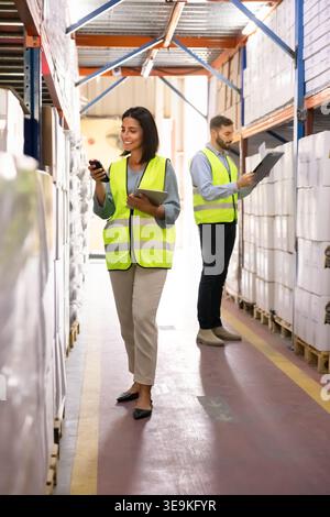 Two warehouse workers checking inventory on shelves stockroom storage Stock Photo