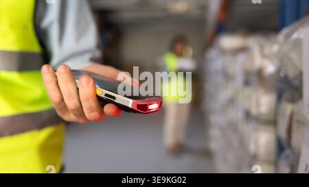 Worker using handheld barcode scanner in industrial warehouse facility, closeup Stock Photo