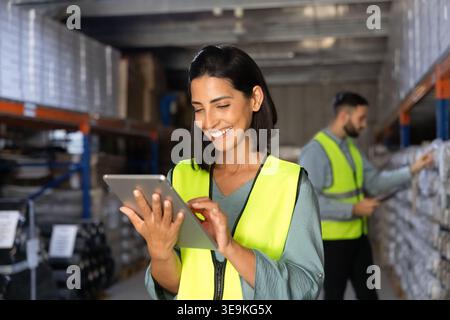 Employee checking stock inventory using digital tablet in warehouse Stock Photo