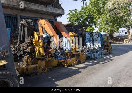 Heavy industrial machinery scrap parts stored outdoor at recycling facility yard under bright sunlight showing obsolete equipment awaiting processing Stock Photo