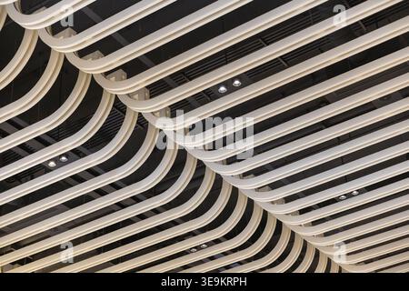 Modern architectural interior ceiling detail showing curved wooden slats and beautiful decorative lights creating interesting geometric patterns and l Stock Photo