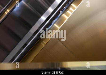 Close up view of shiny brushed brass metal surface with parallel lines reflecting light in modern architectural setting creating feeling of industrial Stock Photo